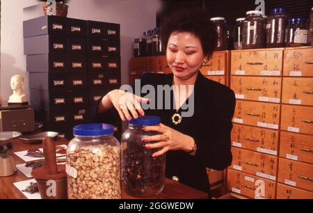 Austin Texas USA, um 1992: Frau entschrauben Deckel auf Krug mit Kräutern in einer chinesischen Kräuterapotheke in einer Akupunkturklinik. ©Bob Daemmrich Stockfoto