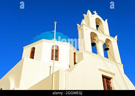 Eine griechisch-blaue Kuppelkirche mit Glockenturm in Oia, Santorini, Griechenland. Stockfoto