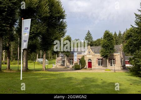 ZUTPHEN, NIEDERLANDE - 21. Aug 2021: Flagge mit Firmenlogo vor dem Gebäude des niederländischen Frischwasserversorgungsunternehmens Vitens in grüner Waldumgebung Stockfoto