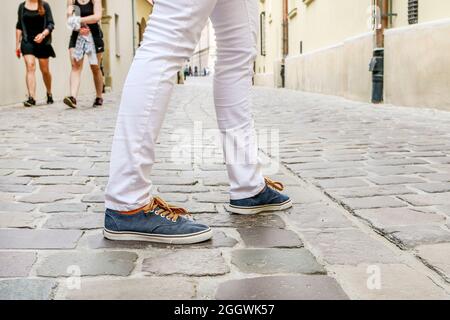 Junge Person in Turnschuhen, die auf der gepflasterten Straße läuft. Reisezeit Stockfoto