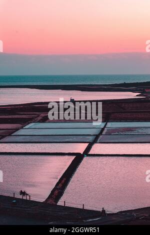 Vertikale Aufnahme von natürlichen Salzverdampfungsteichen bei Sonnenuntergang Stockfoto