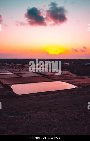Vertikale Aufnahme von natürlichen Salzverdampfungsteichen bei Sonnenuntergang Stockfoto
