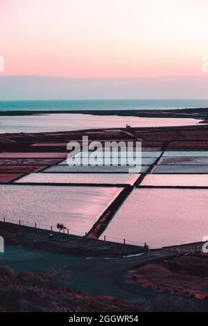 Vertikale Aufnahme von natürlichen Salzverdampfungsteichen bei Sonnenuntergang Stockfoto
