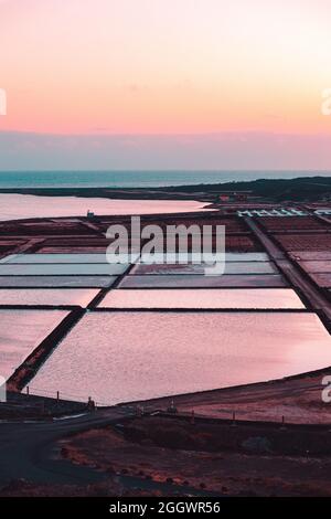 Vertikale Aufnahme von natürlichen Salzverdampfungsteichen bei Sonnenuntergang Stockfoto