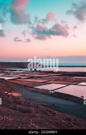 Vertikale Aufnahme von natürlichen Salzverdampfungsteichen bei Sonnenuntergang Stockfoto