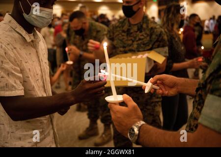 Dienstmitglieder und Familien empfangen und zünden Kerzen während eines Gedenkgottesdienstes und einer Kerzenlichtmahnwache an Bord der Marine Corps Base Hawaii, 29. August 2021. Die Veranstaltung wurde abgehalten, um die 13 Dienstmitglieder zu ehren und zu erinnern, die am 26. August 2021 in Afghanistan getötet wurden. (USA Marine Corps Foto von Gunnery Sgt. Orlando Perez) Stockfoto