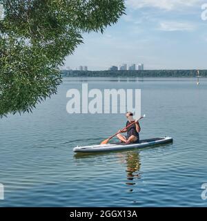 Asiatische ältere Mann auf supboard auf ruhigen See. Stockfoto