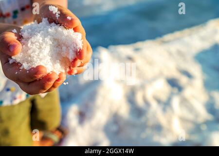 Ein kleiner Junge hält einen frischen Salzkristall in den Händen bei salines in Faro, Algarve, Portugal Stockfoto