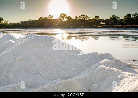 Ein Salzkristalle Haufen neben einem Teich voller Salz nach der Verdunstung von Meerwasser bei salines in Faro, Algarve, Portugal Stockfoto