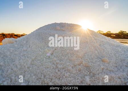 Ein Salzkristalle Haufen neben einem Teich voller Salz nach der Verdunstung von Meerwasser bei salines in Faro, Algarve, Portugal Stockfoto