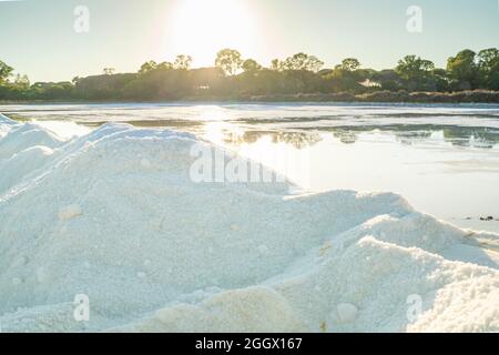 Ein Salzkristalle Haufen neben einem Teich voller Salz nach der Verdunstung von Meerwasser bei salines in Faro, Algarve, Portugal Stockfoto