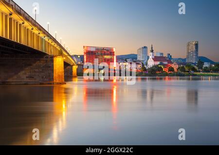 Linz, Österreich. Stadtbild des Flussufers Linz, Österreich bei Sonnenuntergang im Sommer mit Spiegelung der Lichter der Stadt in der Donau. Stockfoto