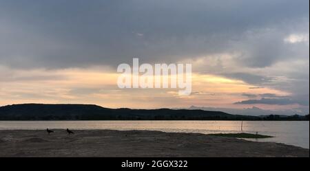 Romantischer Sonnenuntergang mit dem See auf dem Land und bewölktem Himmel in der Dämmerung. Stockfoto