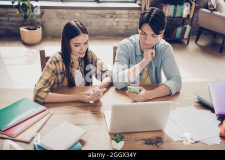 Porträt von zwei attraktiven fokussierten Klassenkameraden Lernenden mit Gadgets Vorbereitung Aufgabe Projekt im Loft industriellen Innenraum Stockfoto