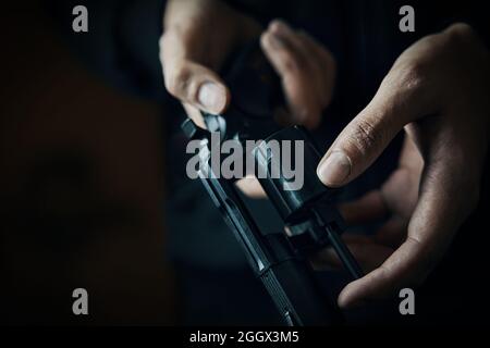 Nahaufnahme der Waffe nachladen. Herrenhände prüfen im Revolverfass auf Kugeln. Person bereitet sich auf Schüsse vor. Schusswaffe zur Verteidigung oder zum Angriff. Stockfoto