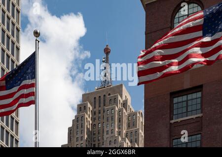 Detroit, Michigan - das Penobscot Building, eingerahmt von Flaggen, die vor dem TCF Convention Center fliegen. Das 47-stöckige Gebäude war das achthöchste Stockfoto