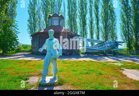 PEREIASLAV, UKRAINE - 22. MAI 2021: Die alte sowjetische Skulptur des Getreidesäwers und des alten Flugzeugs im Hintergrund, Pereiaslav Scansen, am Mai Stockfoto