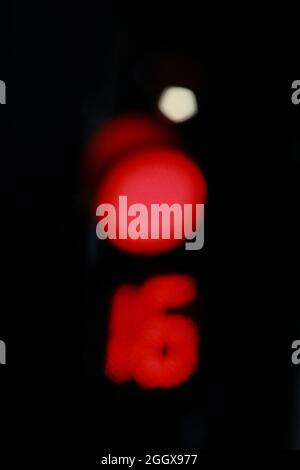 Verwackelte Ampeln mit roter Ampel für Stopp und Countdown 16 auf schwarzem Fokuskonzept Stockfoto