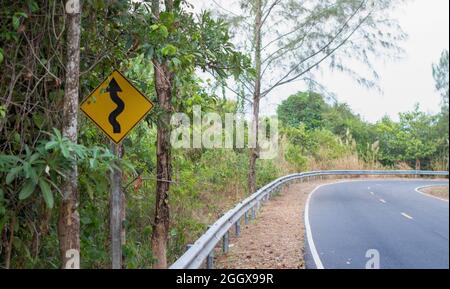 Altes kurvenreicher Straßenschild oder altes kurvenreicher Straßenschild neben der Landstraße, irgendwo mitten im Wald Stockfoto