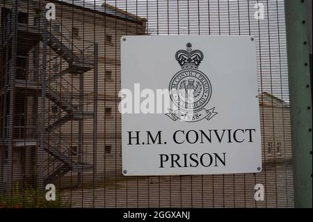 Schild für das HM Convict Prison, das früher ein Gefängnis für höchste Sicherheit war und heute ein Museum und eine beliebte Touristenattraktion ist. Zaun, Gefängnisgebäude, keine Menschen. Stockfoto
