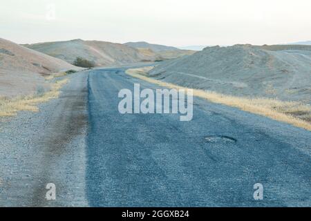 Rissiger Beton auf der Wüstenstraße. Gesprungene Asphaltstraße. Stockfoto