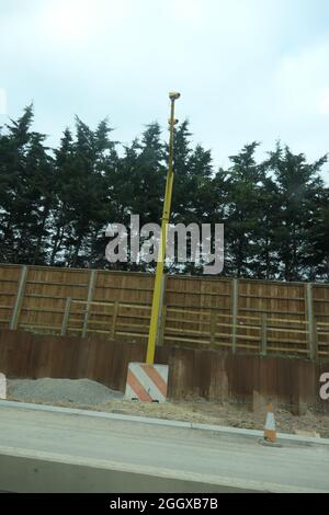 Radarkamera auf der Autobahn M1 Northamptonshire UK Zaun M1 Straßenbauarbeiten Bäume Pelzbarrieren Holz lackiert am Straßenrand Stockfoto