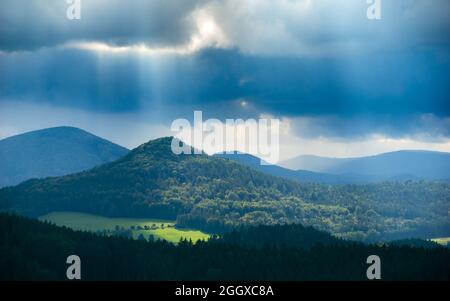 Malerische Aussicht auf den Berg Sokol bei Sonnenschein unter schweren dunklen Sturmwolken, wie vom Berg „Popova skala“ in der Tschechischen republik aus gesehen Stockfoto