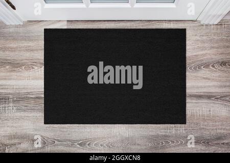 Schwarze Coir-Fußmatte auf Holzboden vor der Tür. Produktmockup Stockfoto
