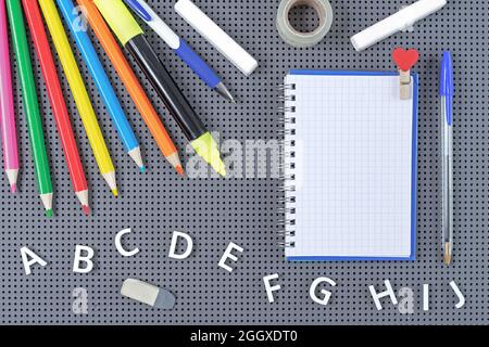 Notizblock auf Spirale, Schulmaterial und Buchstaben des englischen Alphabets. Schulkonzept. Stockfoto