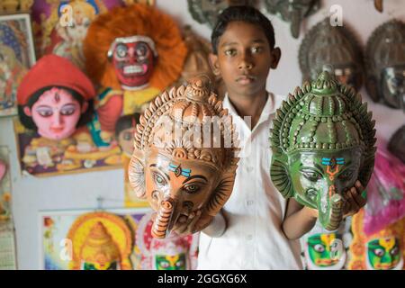 PURULIA, WESTBENGALEN, INDIEN - 15. AUGUST 2017 : Junge mit farbenfroher Chhau (oder Chhou) Maske des hinduistischen Gottes, Lord Ganesha, Kunsthandwerk zum Verkauf. Stockfoto