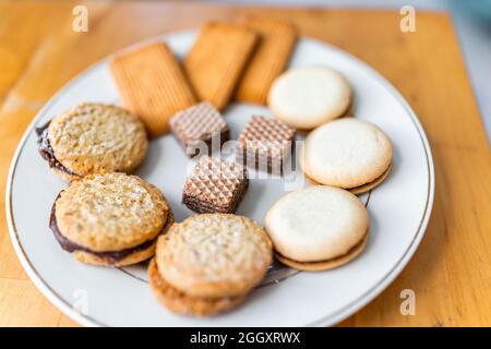 Auswahl an Snacks von Gourmet-Schokoladenkeksen mit Waffeln und süßen Keks mit Füllung auf weißem Teller Makro Nahaufnahme Stockfoto