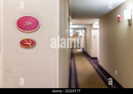 Nahaufnahme des Schildes am Inn Hotel Motel mit der Nummer für das Nichtraucherzimmer und leerem Korridor in der Nacht Stockfoto