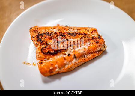 Gegrillter, gebackener oder gebratener Sockeye-Lachs-Fisch mit Meeresfrüchten aus der Nähe oben mit roter Farbe und Omega-3-Nahrung auf weißem Teller mit schwarzer Pfefferwürze Stockfoto