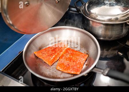 Roher Sockeye Lachs, Fisch mit roter Farbe und Omega-3-Braten in einer Pfanne mit Deckel auf einem Kochfeld Stockfoto