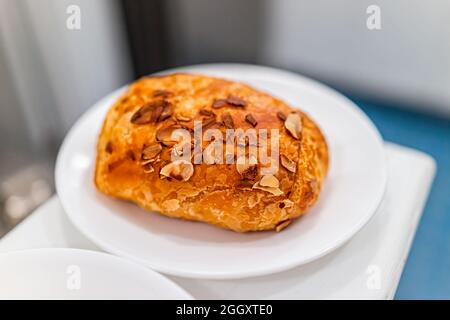 Goldbraun gebackenes Gebäck-Croissant auf Tellern mit schuppiger Kruste und Mandelsahnefüllung als traditionelle französische Küche und Frühstück am Morgen Stockfoto