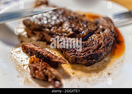 Nahaufnahme des Messerschneidens Schneiden gekocht mittel selten gut gemacht gegrilltes Gras gefüttert Ribeye Rib Eye Fleisch Rindfleisch Steak auf weißem Teller Stockfoto