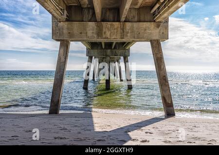 Unter dem berühmten Okaloosa Island Angelpier in Fort Walton Beach, Florida Wintersaison mit Säulen, grüne Wellen in Panhandle, Golf von Mexiko Smaragd c Stockfoto