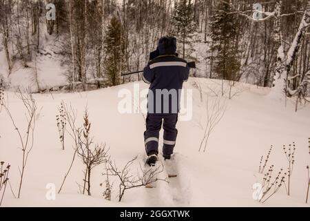 Auf der Suche nach Beute näherte sich der Jäger auf Skiern dem schneebedeckten Hang zum Bach Stockfoto