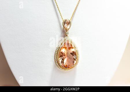 Pfirsich Edelstein Morganit in ovaler Form Anhänger goldene Rose Halskette mit kleinen Diamantschmucksteinen Edelsteine auf Einzelhandel Staffelei mit weißem Hintergrund Stockfoto