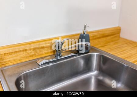 Neue moderne Wasserhahn und Küchenraum Edelstahl Waschbecken Nahaufnahme mit Waschbecken in Holz Arbeitsplatte in Modell Haus Wohnung von Ecke Innenraum Stockfoto
