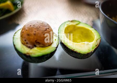 Nahaufnahme von South Florida Sorte von großen grünen frischen rohen fettarmen Avocado in zwei Hälften geschnitten mit großen Saatgrube auf Küchentisch Stockfoto