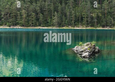 Ein Felsen in einem smaragdgrünen Wasser des Blindsees mit Tannen im Hintergrund Stockfoto