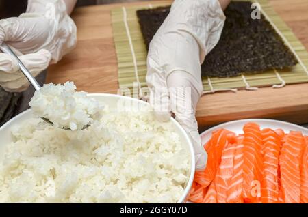 Verwenden von Reis für Sushi, das Verfahren der Herstellung von Sushi mit Lachs und Avocado Stockfoto