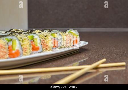 Frisches, köstliches japanisches Sushi mit Avocado, Gurken, Garnelen und Nahaufnahme. Stockfoto