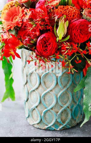 Roter und oranger Strauß mit Rosen, Gerberas, Nelken und Freesias. Inneneinrichtung Stockfoto