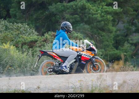 Lernender Motorradfahrer, der auf seinem Repsol-Motorrad, Wiltshire, Großbritannien, eine Staubspur fährt Stockfoto