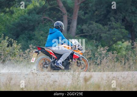 Lernender Motorradfahrer, der auf seinem Repsol-Motorrad, Wiltshire, Großbritannien, eine Staubspur fährt Stockfoto