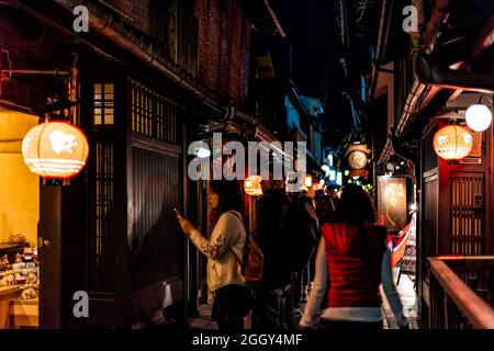 Kyoto, Japan - 16. April 2019: In der dunklen, schmalen, berühmten Straße Pontocho, in der sich die Menschen nachts mit beleuchteten Laternen und einem nahe gelegenen Izakaya-Restaurant treffen Stockfoto