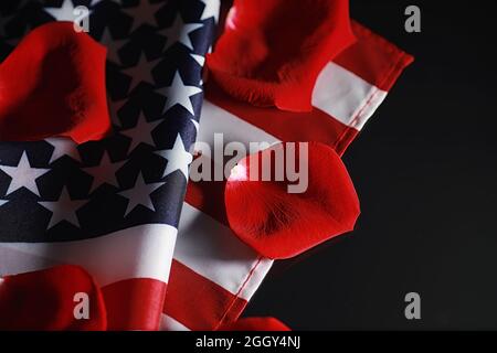 Amerikanische Flagge und Rosenblume auf dem Tisch. Symbol der Vereinigten Staaten von Amerika und rote Blütenblätter. Patriotismus und Erinnerung. Stockfoto