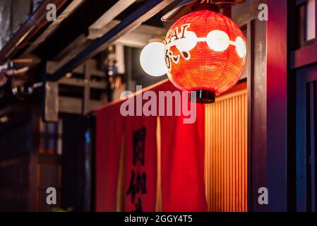 Kyoto, Japan - 16. April 2019: Dunkelschwarzer Abend im Gion-Viertel mit traditioneller roter Papierlaterne auf den Vorhängen des Restauranteingangs Stockfoto